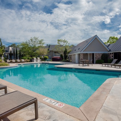 Outdoor community swimming pool at Arbors at Brookfield apartments in Mauldin, SC with the pool house in the background